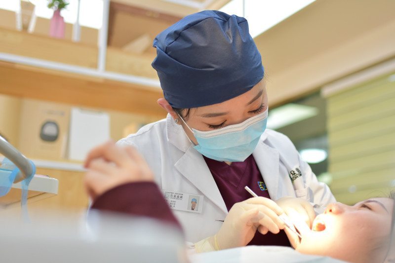A dentist in a mask examining a patient at a dentist’s office.